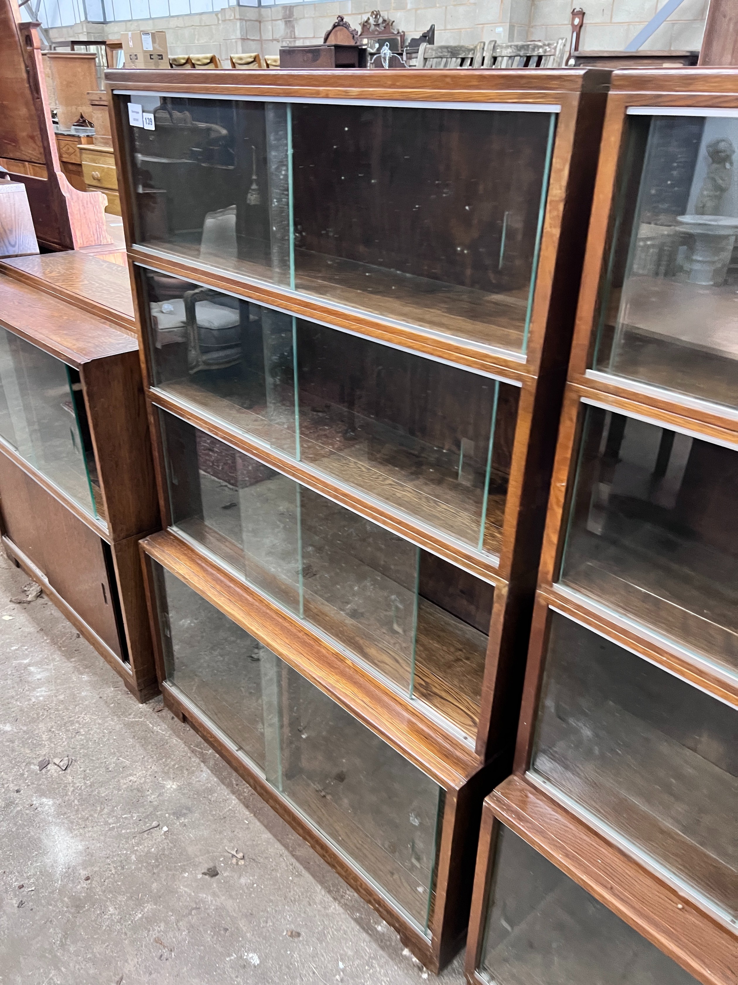 Five 1960's oak Minty bookcases comprising two four section, one three section, and a near pair of two section bookcases, widest 89cm, depth 30cm, height 135cm *Please note the sale commences at 9am.